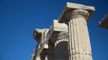 Bir Yunan tapınağının derin mavi gökyüzündeki eski sütunlarının ayrıntıları.