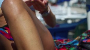 Güneş kremi süren bir kızın bacağına yaklaş.