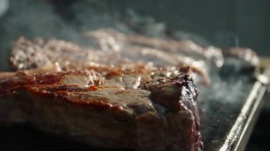 Sıcak bir tabakta iki büyük biftek ve sigara.