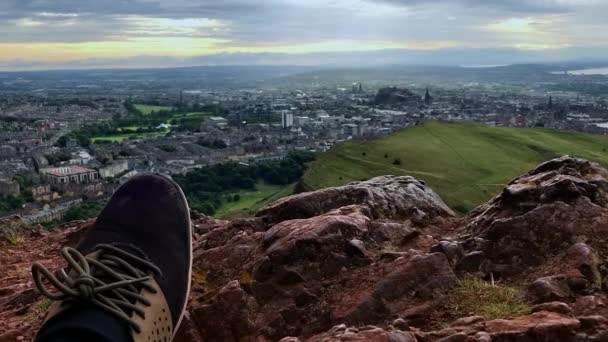 远足之后 一只鞋子踩在岩石上 以爱丁堡为背景 — 图库视频影像