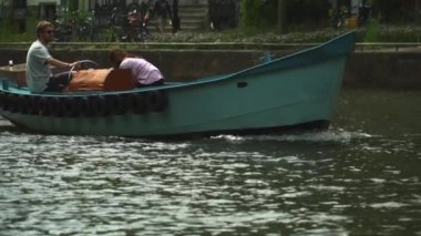 Amsterdam, Hollanda - 08: 12 Açık mavi tekne 2 gençle birlikte ağır çekimde geçiyor