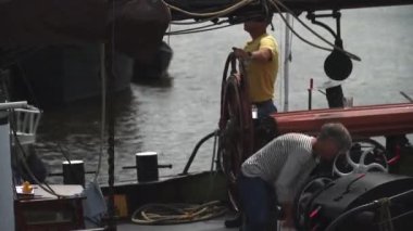 Teknede çalışan bir kadın ve dümeni süren bir adam.