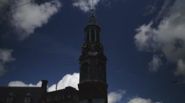 Ortaçağ saat kulesinin zaman atlaması. Amsterdam 'ın merkezinde. Mavi gökyüzü ve hareket eden bulutlar.