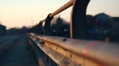 Gün batımında yol kenarındaki metal korkuluklardan geçen arabaların gölgeleri...