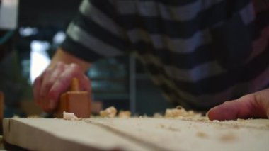 Yavaş çekimde ahşap döşeyen bir adamın eline yaklaş ve sörf tahtası yap.