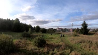 Bir FPV 'nin üzerinde at sırtında uçarken, at üstünde bir kız, yeşil bir tarlada, ormanın arka planında, çalılarda, ağaçlarda, mavi gökyüzünde, beyaz bulutlarda