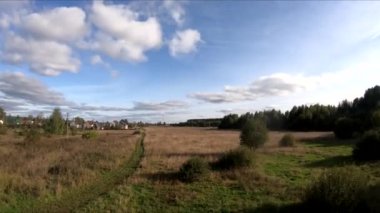 Bir FPV 'nin üzerinde at sırtında uçarken, at üstünde bir kız, yeşil bir tarlada, ormanın arka planında, çalılarda, ağaçlarda, mavi gökyüzünde, beyaz bulutlarda