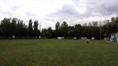 İnsanların yeşil çimlerde futbol oynadığı stadyumda uçarak.