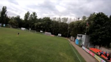 İnsanların yeşil çimlerde futbol oynadığı stadyumda uçarak.