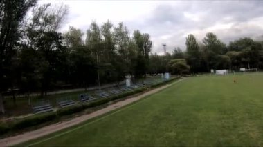 İnsanların yeşil çimlerde futbol oynadığı stadyumda uçarak.