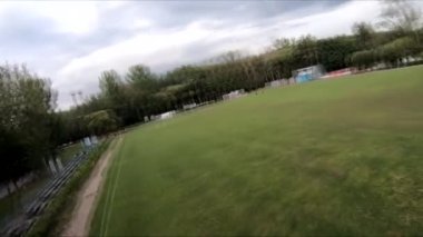 İnsanların yeşil çimlerde futbol oynadığı stadyumda uçarak.