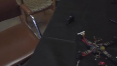 Parçalanmış FPV kuadrokopteri, siyah bir masanın üzerine kendin yap drone onarımı, eski plastik bir çerçevenin çıkarılması, kırık parçalar, İngiliz anahtarı ve tornavida ile sökülmesi, elektronik, mikro devreler, tamir, lehimleme.