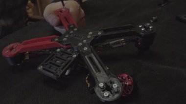 Parçalanmış FPV kuadrokopteri, siyah bir masanın üzerine kendin yap drone onarımı, eski plastik bir çerçevenin çıkarılması, kırık parçalar, İngiliz anahtarı ve tornavida ile sökülmesi, elektronik, mikro devreler, tamir, lehimleme.