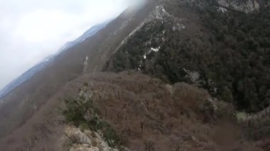 fpv Quadcopter uçuşu dağlarda, Sochi, çimen bir açıklıkta, gri yeşil orman, güzel yüksek kayalar, büyük taşlar, mavi gökyüzü ve deniz ufukta