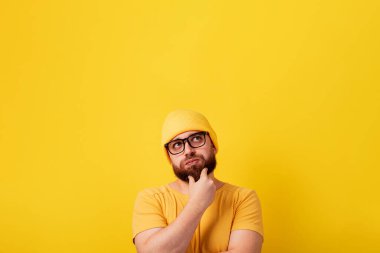 Düşünen sakallı adam sarı arkaplana bakıyor, plan alanı olan bir resim