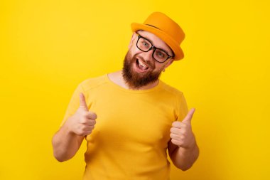 Adam sarı arka planda el hareketi yapıyor.