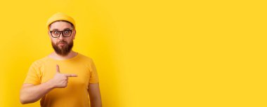 Boş alanı işaret eden modaya uygun sakallı adam. Reklam için geniş panoramik düzen.