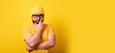 Düşünen adam sarı arka planda, ciddi adam düşünüyor, panoramik düzende mesaj için yer var