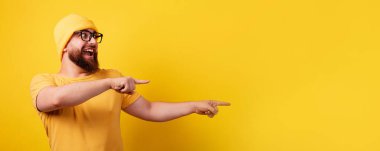 man pointing over empty space, panoramic layout, guy over yellow background