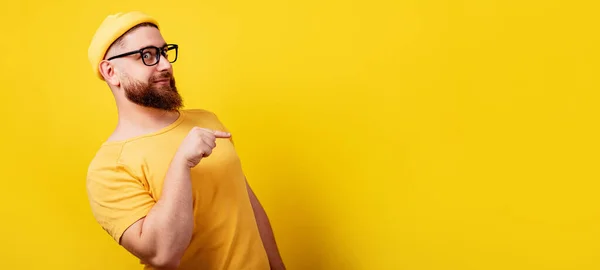 Smiling Bearded Man Glasses Pointing Empty Yellow Background Panoramic Layout — Stockfoto