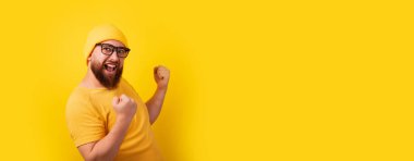 Sarı arka planda başarılı sakallı adam, kazanan jest, panoramik pankart