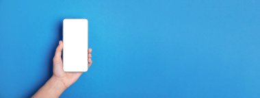Mavi arkaplan üzerinde beyaz boş ekran ile el ele tutuşan cep telefonu, panoramik düzen