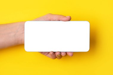 Sarı arkaplan üzerinde beyaz ekran olan akıllı telefonu tut, görüntünün düzeni