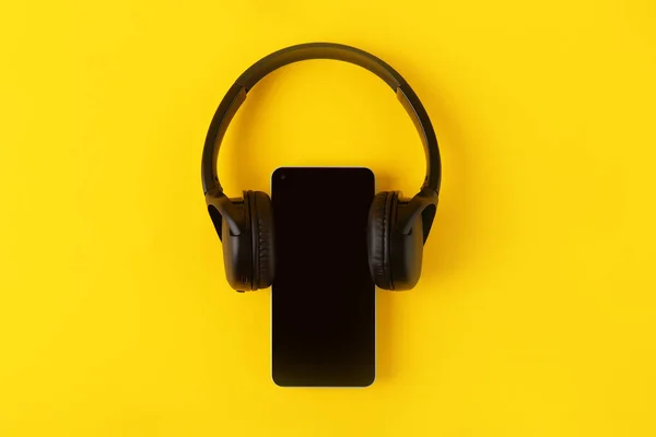 노란색 배경에 헤드폰을 스마트폰 — 스톡 사진
