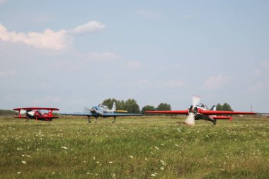 Tyumen, Rusya, 18 Ağustos 2016: Küçük uçakların pilotları çimlerden kalkan bir yaz sahasında gösteri uçuşları düzenliyor. Akrobaside aşırı yüklenme