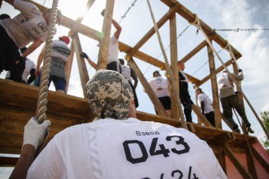 Tyumen, Rusya, 11 Haziran 2016: Hayatta kalma mücadelesi, takım engelli bir pistte koşuyor, yangın, çamur, su ve ahşap yapılar, yüksek duvar ve araba tekerleklerinin arasından rögar deliği