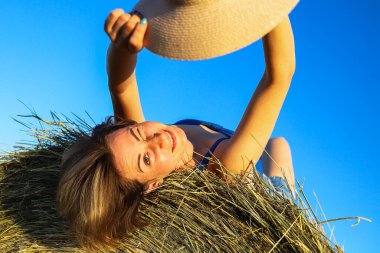 Açık arazide samanlıkta dinlenen bir kız.