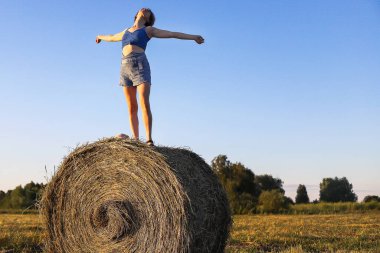 Açık arazide samanlıkta dinlenen bir kız.