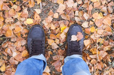 Sarı ve kuru yapraklar ve bacaklar üzerinde sonbahar çizmeleri