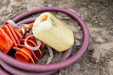 İnşaat hortumu, su kabı ve turuncu koniler yine yerde.