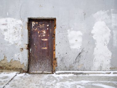 Eski bir kapı çatlak bir binaya erişim sağlar.