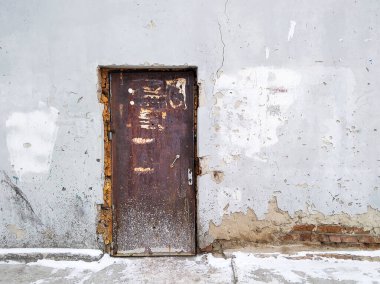 Eski bir kapı çatlak bir binaya erişim sağlar.