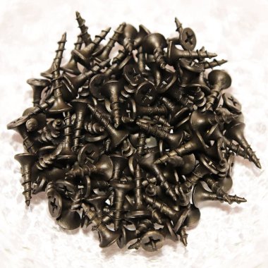 Black shiny screws self-tapping screws lie in a heap