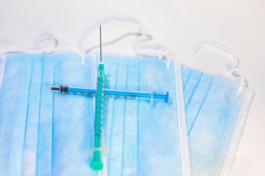 Beyaz bir geçmişi olan mavi bir maske ve sağlık çalışanları ve risk altındaki insanlar için enjeksiyon için bir şırınga. SARS-CoV-2 'ye karşı aşı ile tedavi. Boşluğu kopyala.