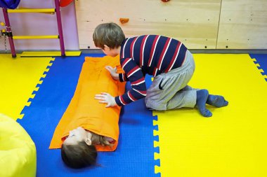 Erkek ve kız çocuklar birbirlerini kalın bir battaniyeye sarıp ıslah merkezinde otizm tedavisi için küçük bir alanı kontrol ediyorlar.