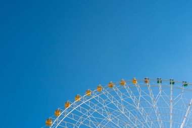 Mavi gökyüzünün altındaki dönme dolabın detaylı görüntüsü.