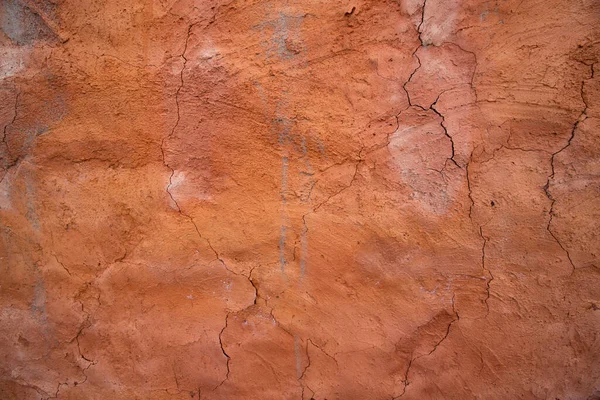 The texture of a red concrete wall with cracks and scratches can be used as a background