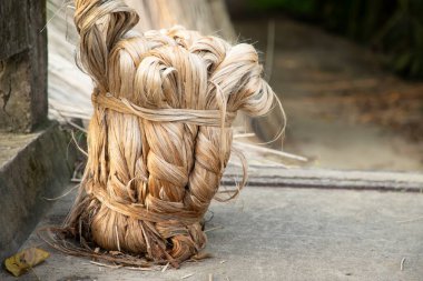 Yerde kalın, kahverengi bir demet çiğ jüt var.  