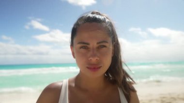 Cancun Sahili 'nde duran mutlu genç kadın. Rüzgarlı saçları olan duyarlı bir kadın kameraya bakıyor. Cancun Mexico 'da yaz tatili boyunca beyaz bikini giyiyor..