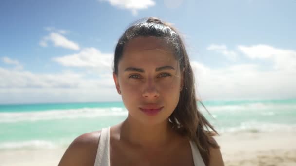 Boldog fiatal nő áll Cancun Beach-en. Érzékeny nő szélfútta hajjal a kamerába néz. Fehér bikini felsőben van a nyári vakáció alatt Cancun Mexikóban.. — Stock videók