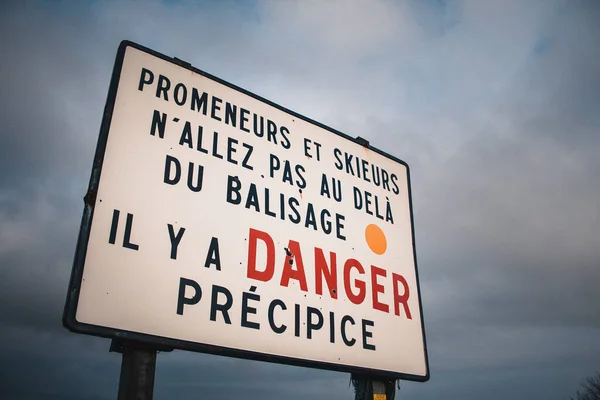 Mountain warning sign translating danger for hikers cliff drop in french, in Ballon d\'Alsace, Vosges, France