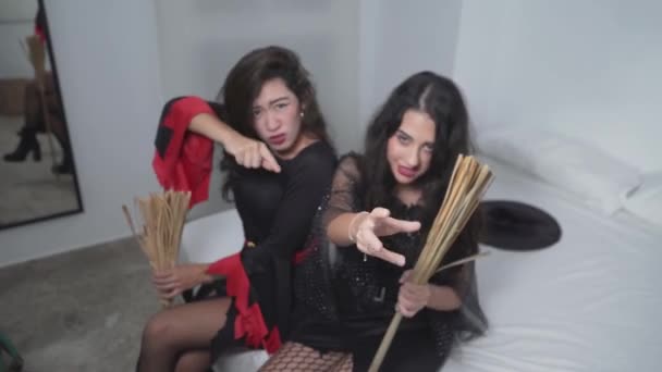 Dua Lovely Colombian Women In Halloween Costumes Sitting On Bed And Acting Like A Witch Looking At The Camera (dalam bahasa Inggris). Konsep Halloween. Medium Ditembak — Stok Video