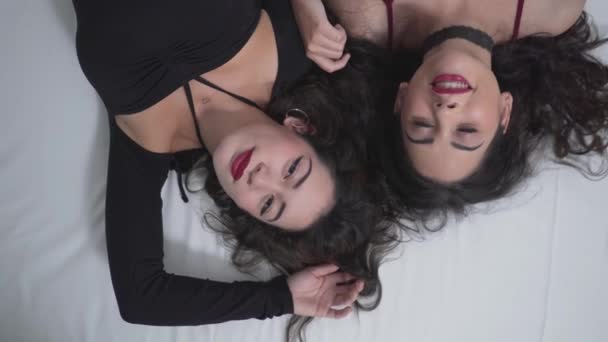 Due affascinanti ragazze colombiane rilassanti mentre si sdraiano sul letto. Rilassarsi prima di andare a una festa di Halloween. - Colpo ad angolo alto, Zoom Out — Video Stock
