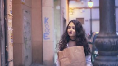 Kağıt çantalı güzel İspanyol kadın apartman dairesine geliyor, duvardaki video interkom 'da basılıyor. orta çekim