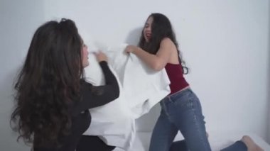 Yatakta yastık savaşı yapan iki Kolombiyalı arkadaş. - Orta boy.