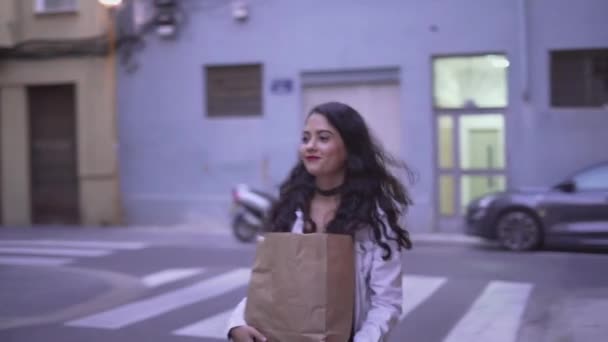 Mujer joven española caminando por la calle y llevando una bolsa de papel marrón. - tiro de seguimiento — Vídeos de Stock